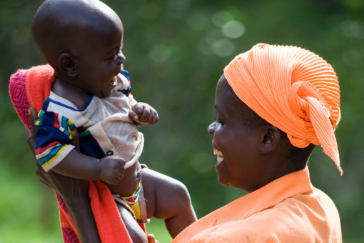 African mother raises her baby up in the air while both smiling
