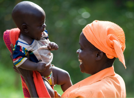 African mother raises her baby up in the air while both smiling